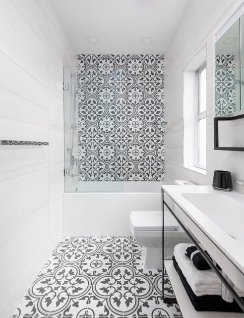 Bathroom floor featuring bold black-and-white abstract patterned tiles.