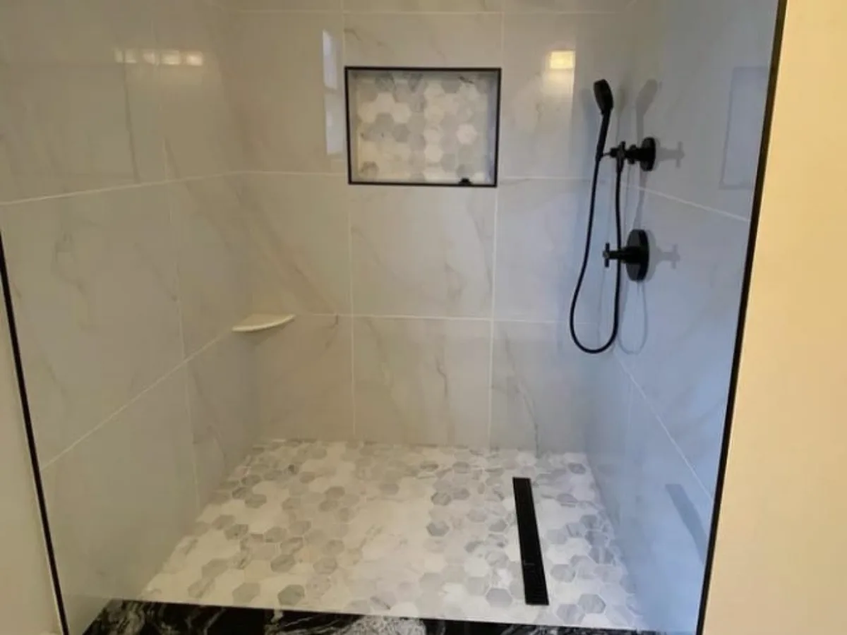 Large format porcelain tile shower walls with honeycomb marble niche and floor