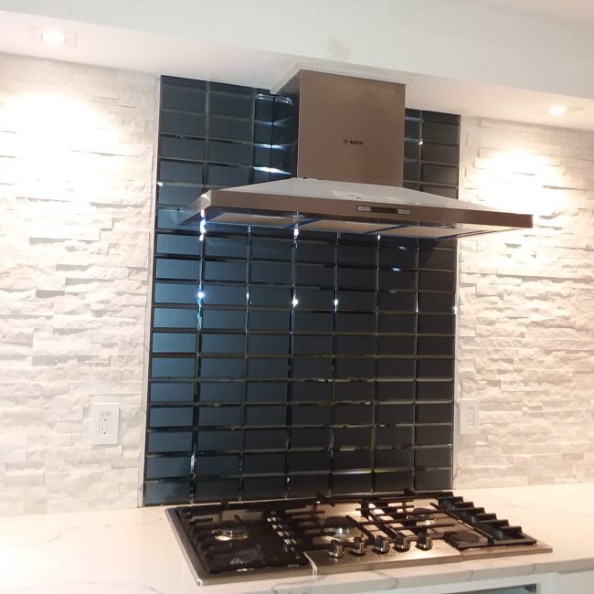 Black Glass & Stacked Stone Backsplash Black glass and stacked stone tile backsplash with a mix of shine and texture in a contemporary kitchen