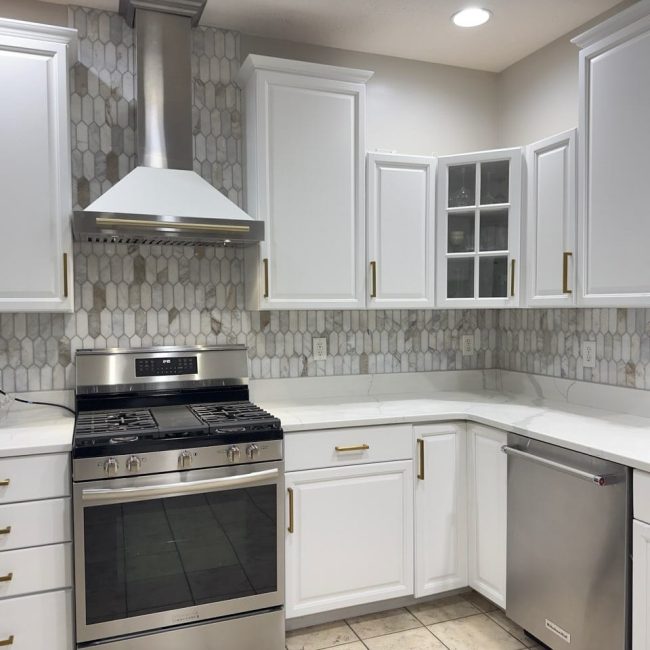 Picket Style Marble Backsplash Ceiling-high picket-style marble tile backsplash in a white kitchen with stainless steel stove